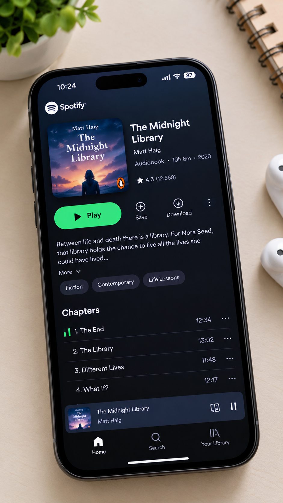 A smartphone displaying Spotify’s audiobook page for The Midnight Library by Matt Haig, showing the book cover, title, author, play button, and audiobook chapters.
