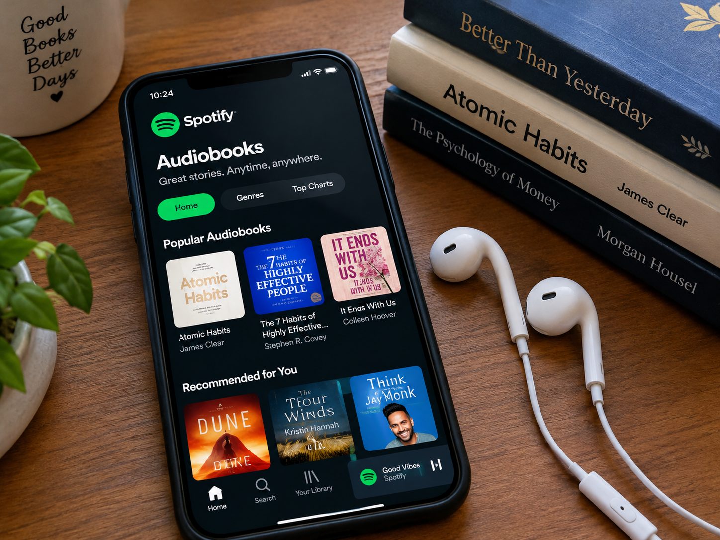 A photo that's Spotify app is open beside books or earphone